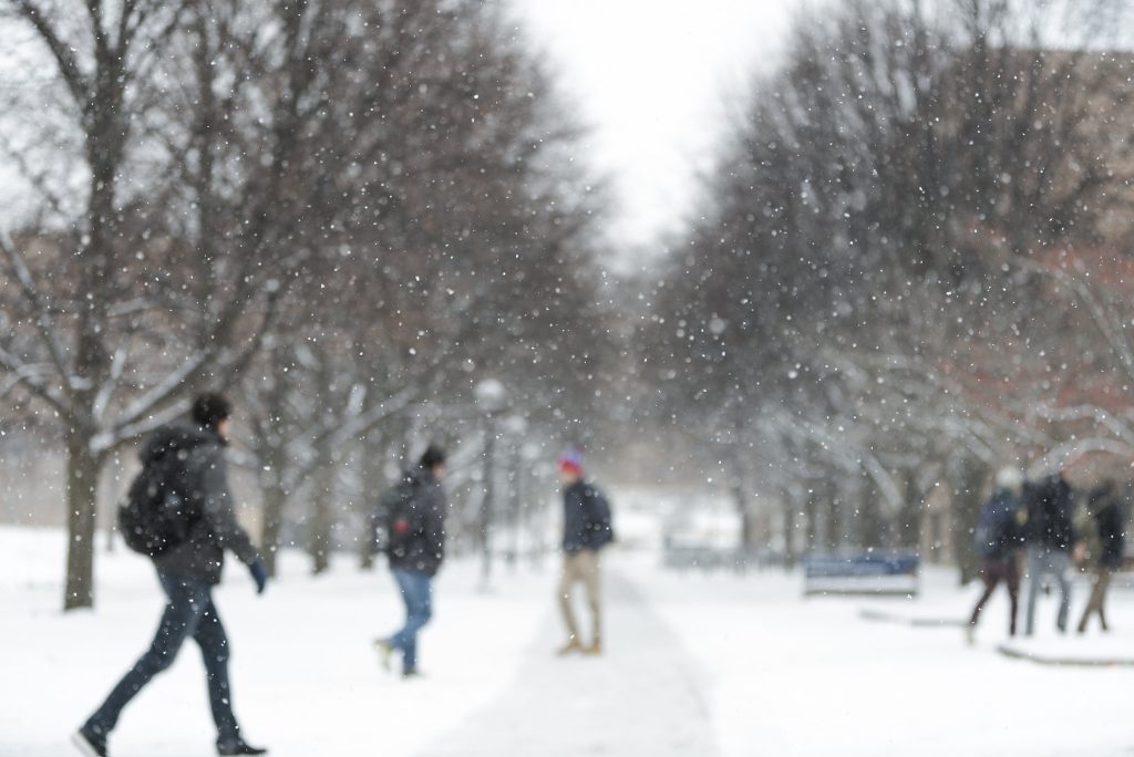 Out of focus students walking to class on a snow filled University of Michigan campus.