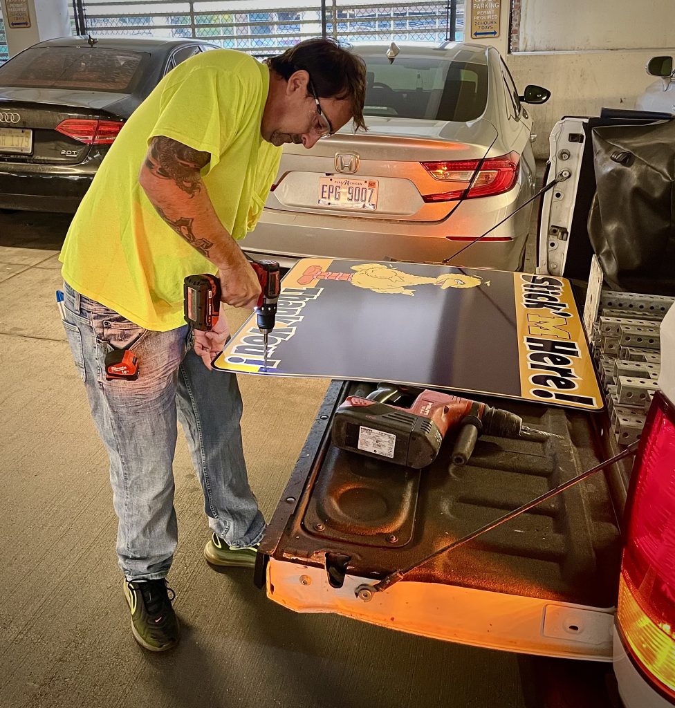 Joe Hatfield prepping Stick'M Here signs for hanging in the parking structure