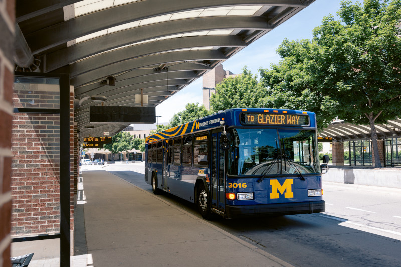 A blue bus pulls into the Central Campus Transit Center. The display on the top of the bus reads To Glazier Way.