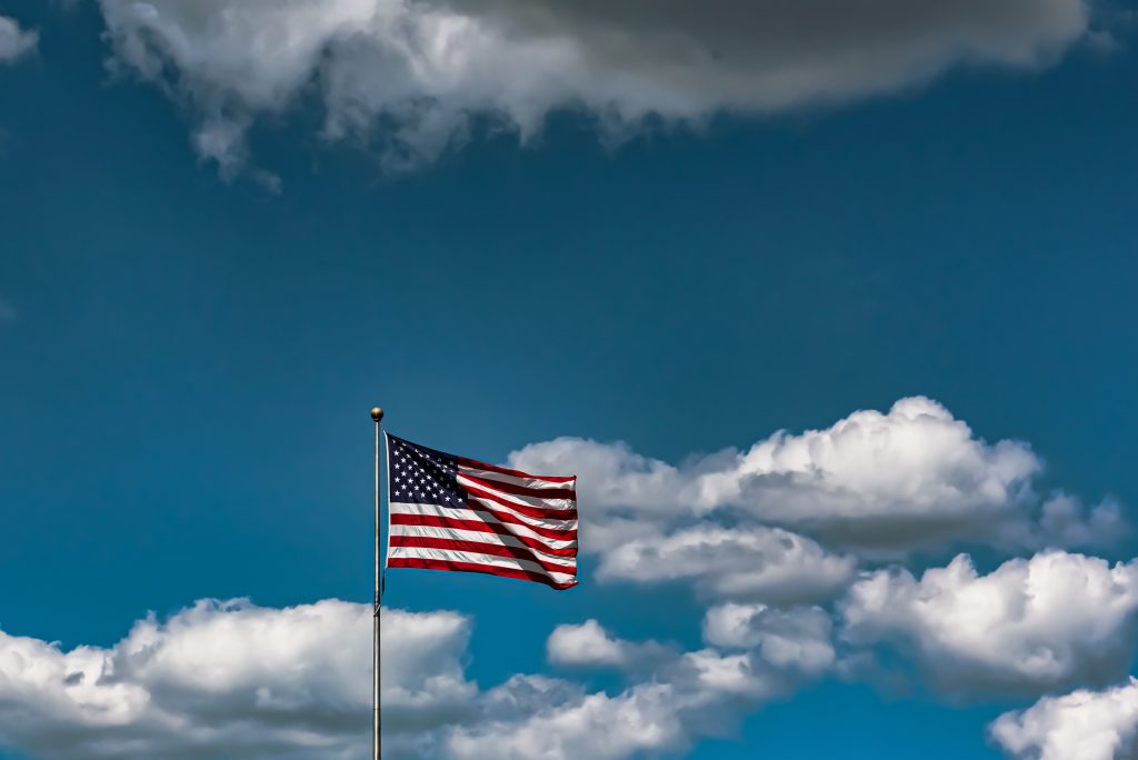 A closeup shot of the American flag waving in the air under a cloudy sky